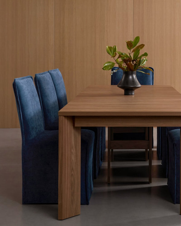 Lifestyle image of a 19-inch back dining chair in Sumi fabric paired with an extendable walnut dining table, highlighting the extendable dining table collection.
