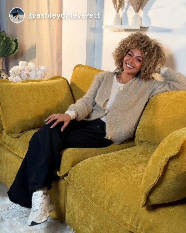 Lifestyle image of a woman sitting on a Modular Performance 2-Seater in Kiro fabric, shown in a real customer home setting