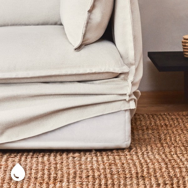 Close-up of an Eggshell fabric end chair with the slipcover partially lifted, highlighting removable machine-washable and interchangeable slipcovers.